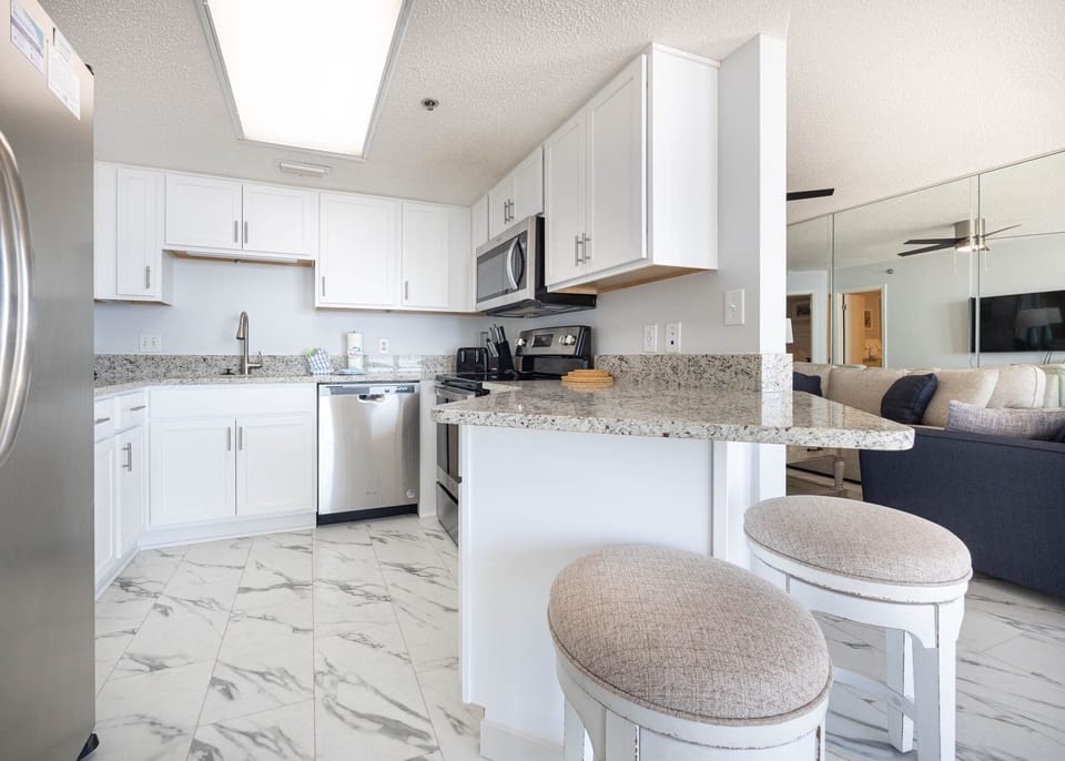 Bright, fully-equipped kitchen with stylish countertops, sleek appliances, and a breakfast bar with comfortable seating