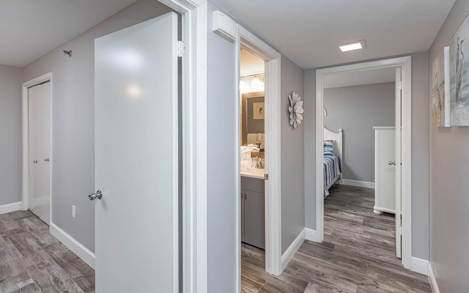 Step into a welcoming hallway that leads to a bright bathroom and a cozy bedroom with charming decor and soft bedding