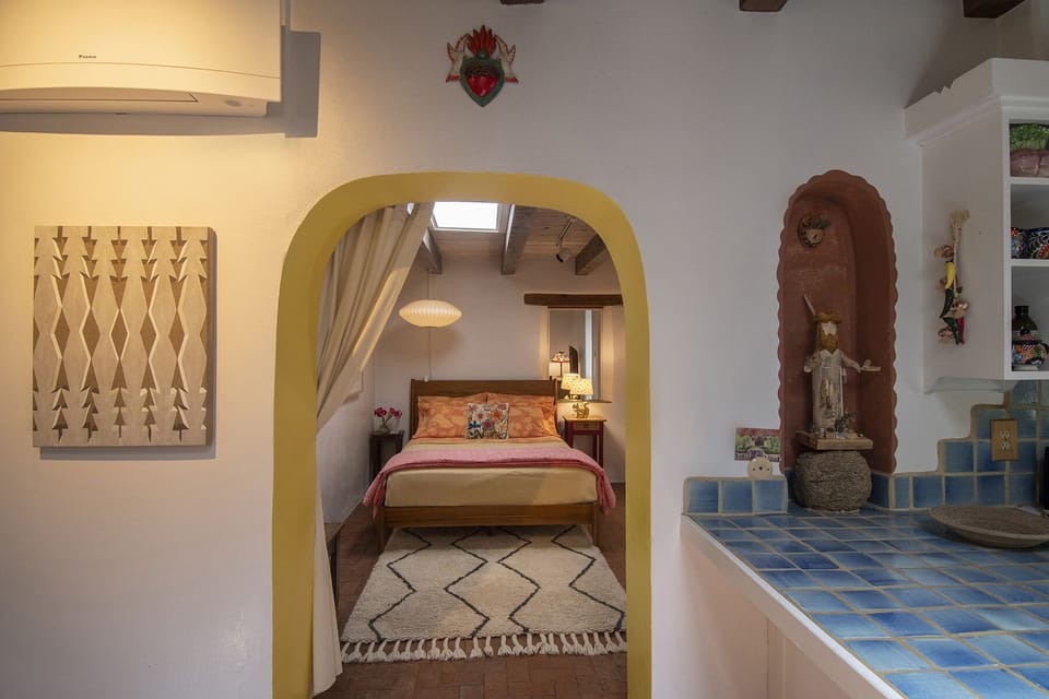 Bright yellow arch into bedroom flanked by Santa Fe painting & Don Pasquale 