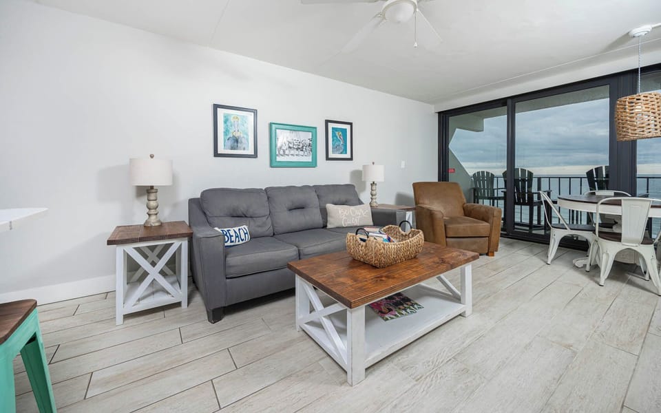 The inviting living room features a comfortable sofa, a stylish coffee table, and a stunning beachfront view from the balcony