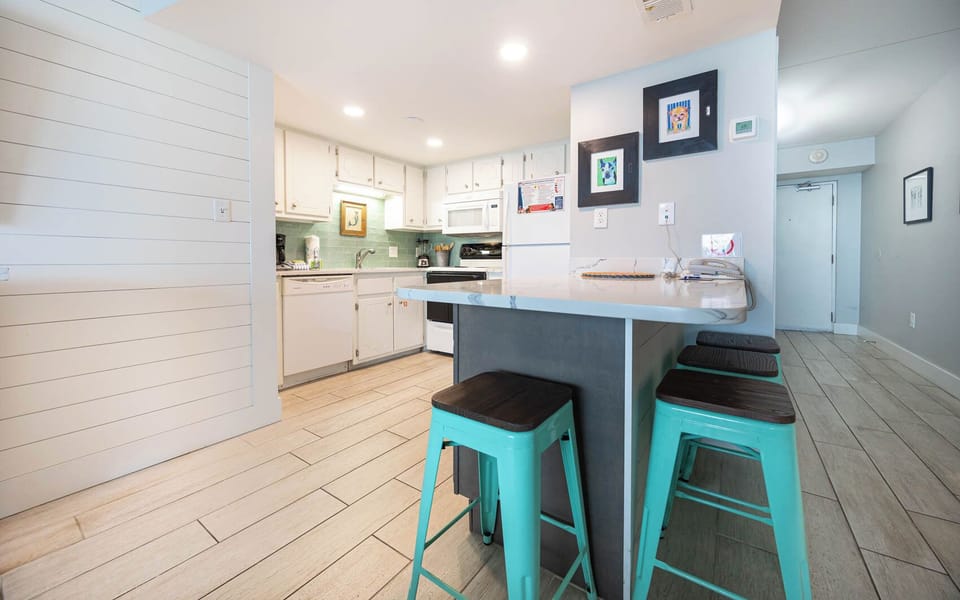 This inviting kitchen features bright cabinetry, modern appliances, and a stylish bar area perfect for casual dining