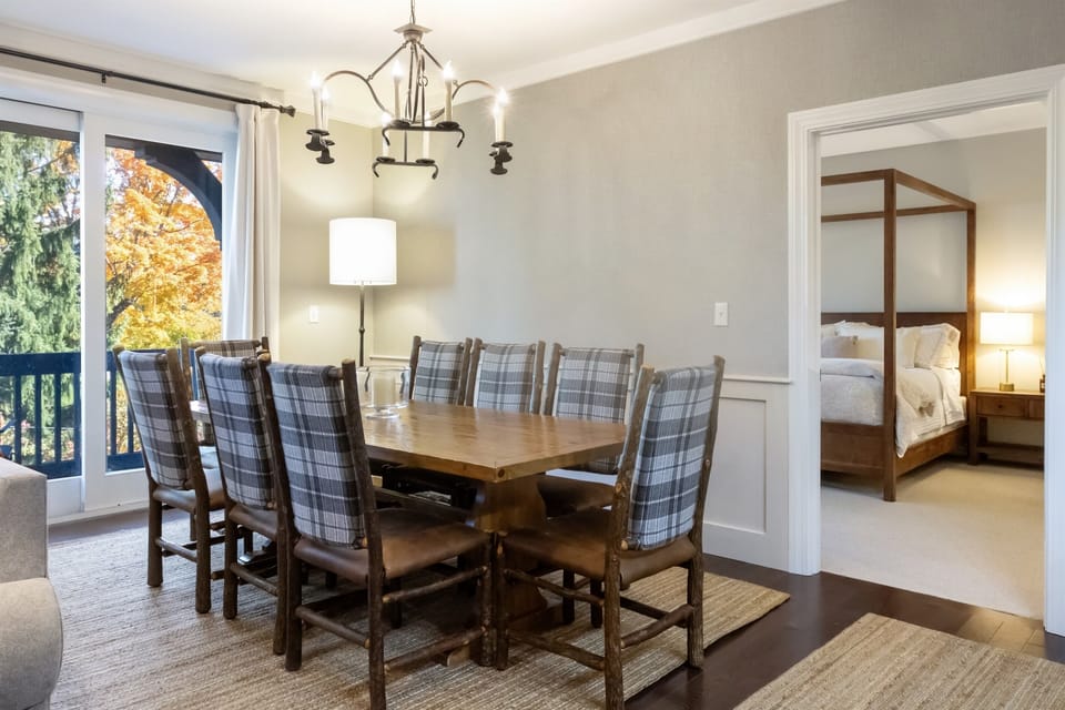 - Inviting dining room with plaid chairs and warm wood table   - Opens to scenic balcony with colorful forest views   - Perfect setting for family meals and cozy mountain mornings