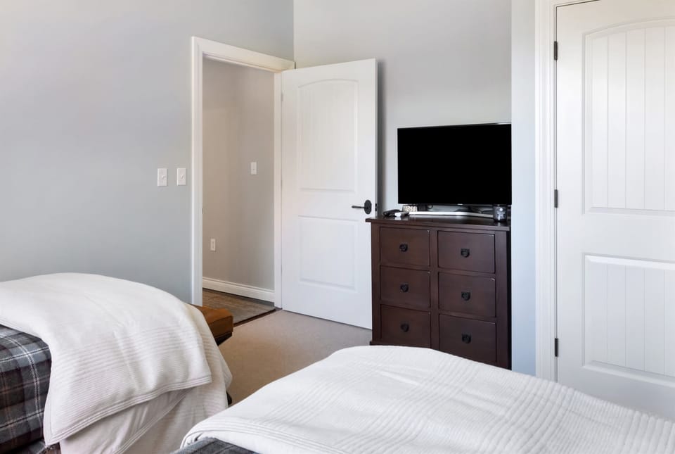 - Twin bedroom with dresser, TV, and mountain charm   - Neutral tones and soft lighting for a relaxing retreat   - Great for guests who enjoy quiet comfort and privacy
