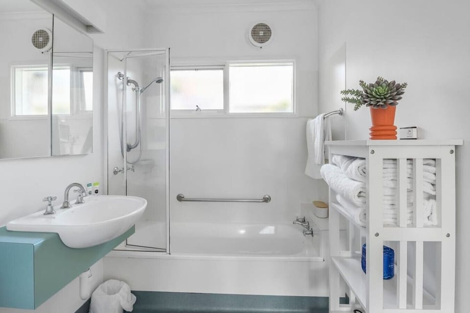 Private bathroom with shower over bath, fresh towels and clean modern finishes.