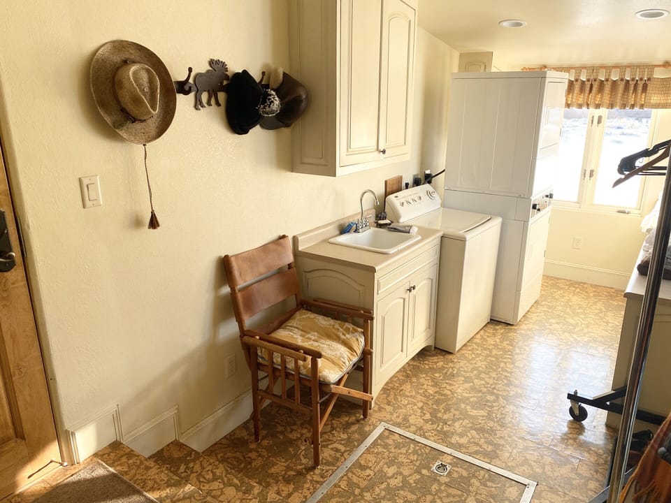 Spacious mud room with washer and commercial dryers and a large rack for  gear.