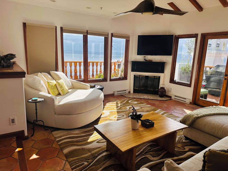 - Kick back in a cozy swivel lounger surrounded by sunshine and scenic ocean views
- Enjoy a movie night or fireside chat in this bright, inviting living space
- Thoughtful touches like throw pillows and textured rugs make this spot feel like home