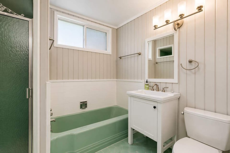 Clean and cozy bathroom featuring a full tub, simple vanity, and fresh lighting for everyday comfort.