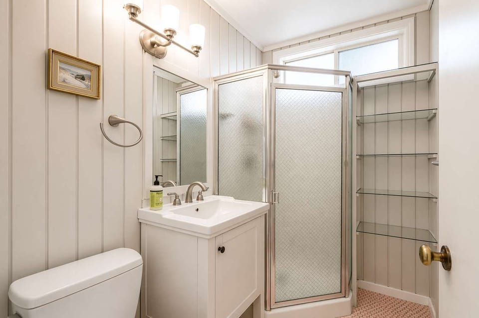 Functional bathroom with a glass shower, bright lighting, and simple design for a comfortable stay. 🚿✨