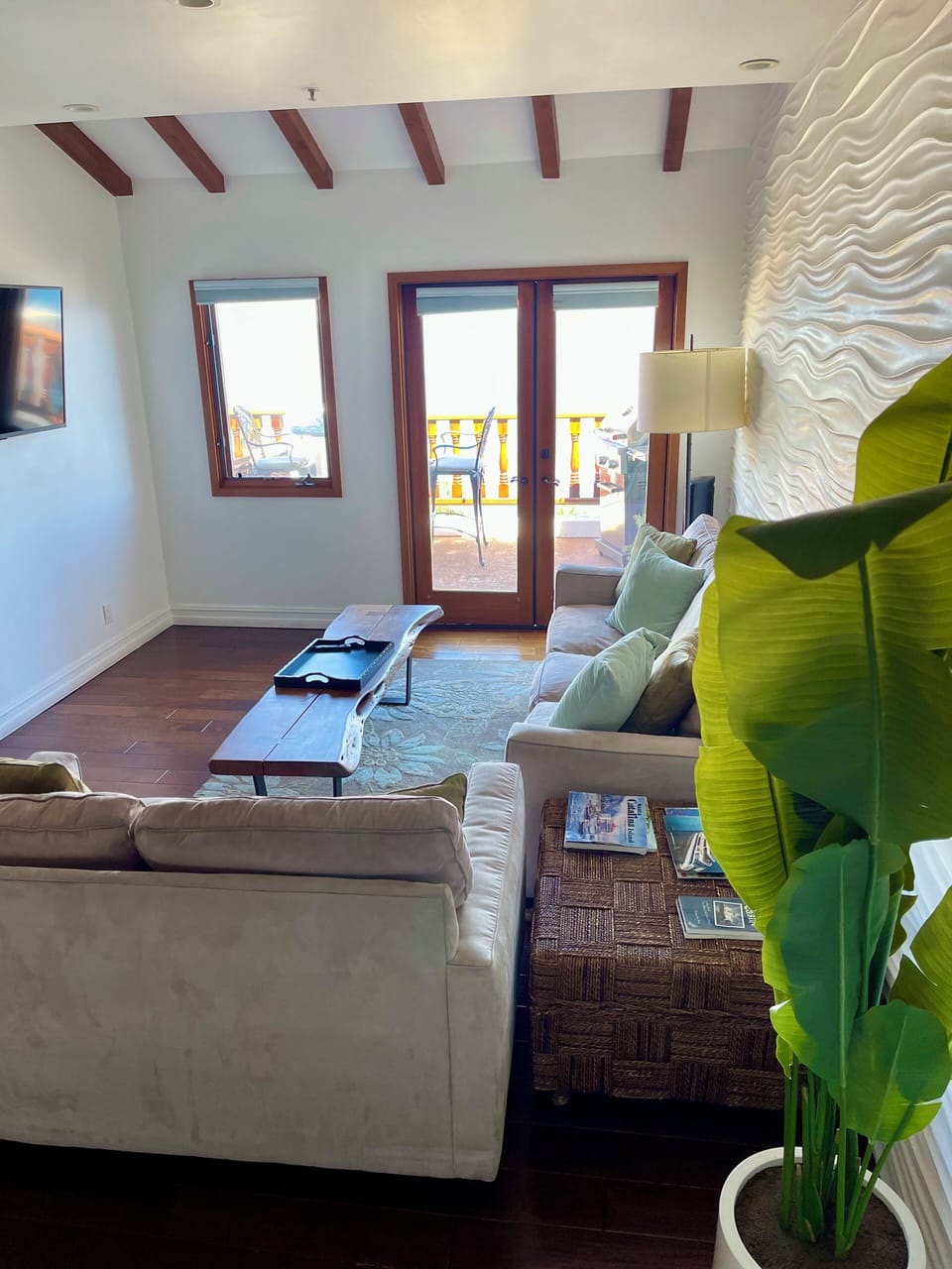 - Sun drenched living room with plush seating, earthy tones, and ocean air at your door
- Vaulted wood beams and a statement wave wall add style and depth
- Steps into your private balcony, ideal for morning coffee or golden sunsets