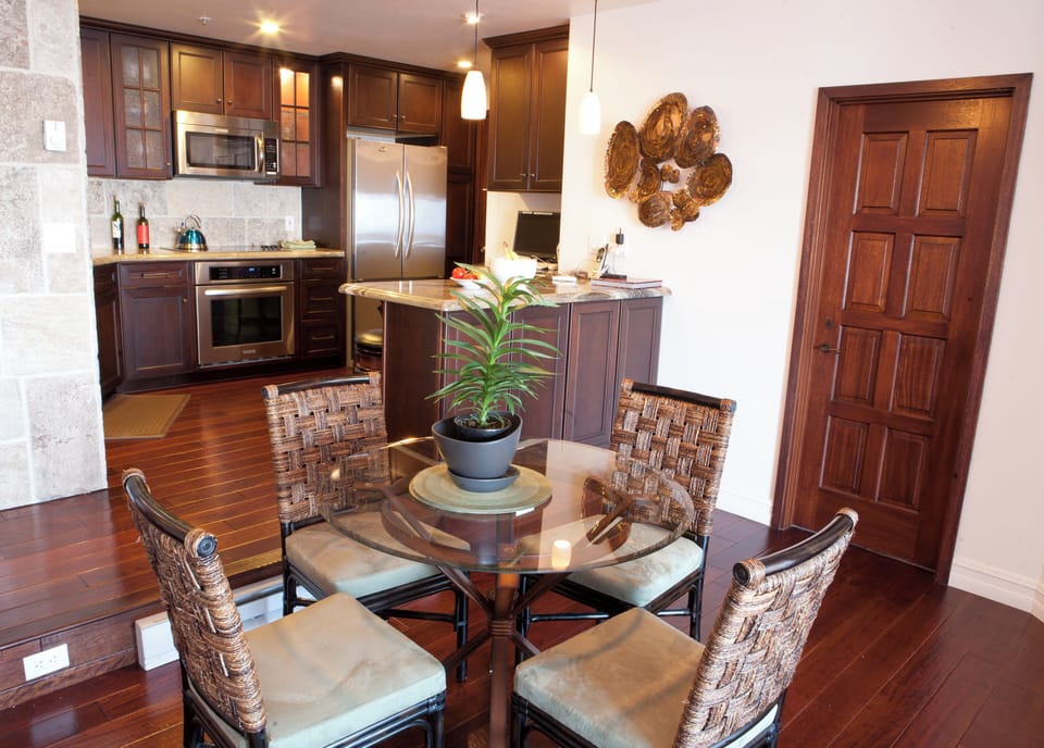 - Enjoy meals at a cozy glass top table surrounded by stylish woven chairs
- Open concept kitchen features stainless appliances, pendant lighting, and granite counters
- Artistic wall accents and rich wood tones create a warm, inviting atmosphere