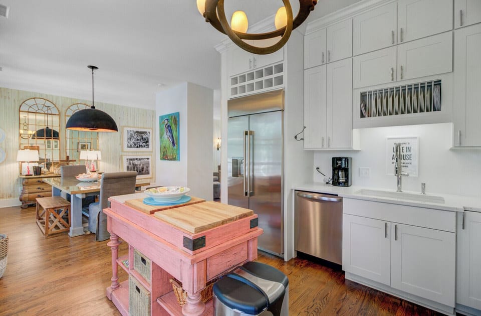 Your bright open kitchen flows seamlessly into the living space, featuring white cabinetry, stainless appliances, and a charming pink island for cooking adventures.
