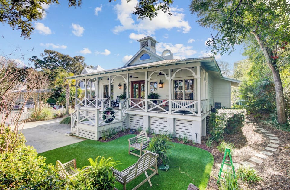 Charming cottage features wraparound porch and private garden oasis with lush landscaping and peaceful seating areas.