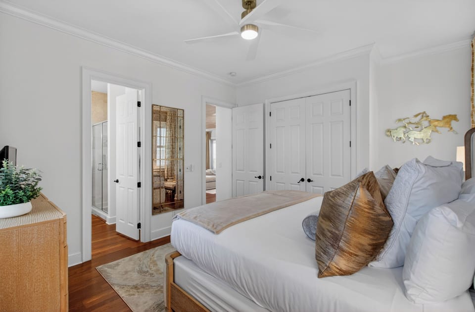 Sink into crisp white linens and natural textures in your serene bedroom, where warm wood floors and coastal accents create the perfect retreat.