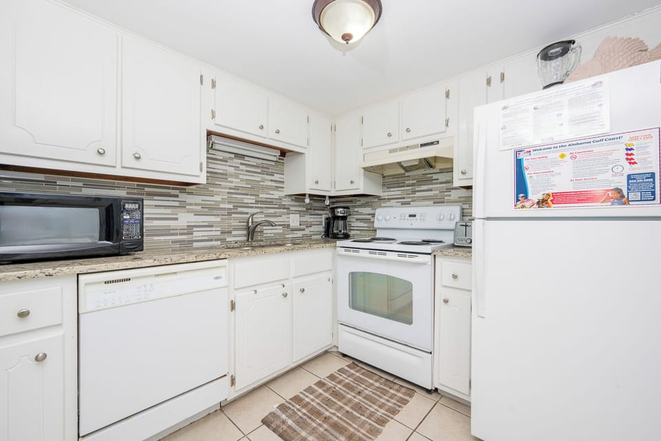 The kitchen features white cabinets, granite countertops, and white appliances, perfect for preparing meals during your stay