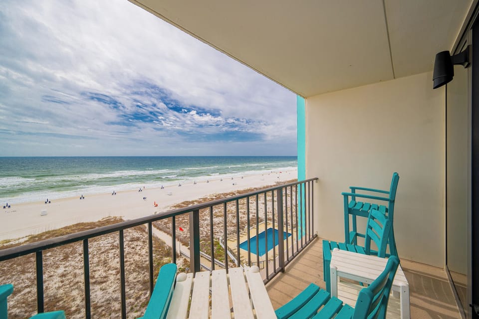 Enjoy stunning beachfront views from this cozy balcony, complete with comfortable seating for relaxation