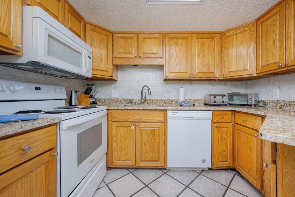 Bright granite counters complement warm oak cabinets as you prepare beachside meals in the kitchen
