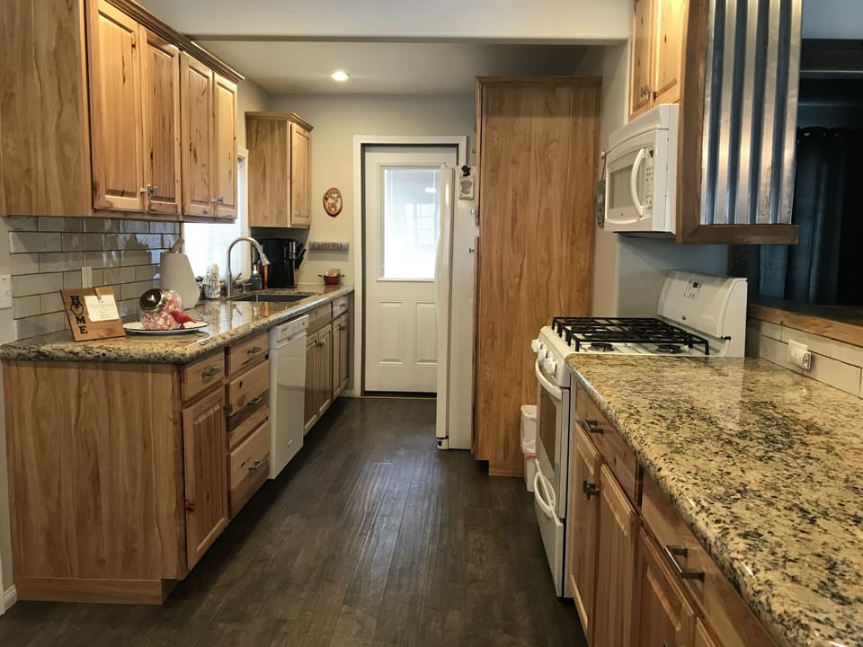Beautiful kitchen leads to back porch with deck seating & Weber propane BBQ.