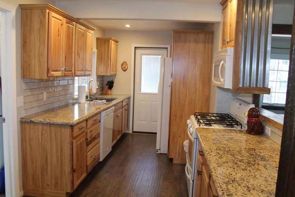 Kitchen is fully stocked with cooking/baking ware,  utensils, dining/glassware