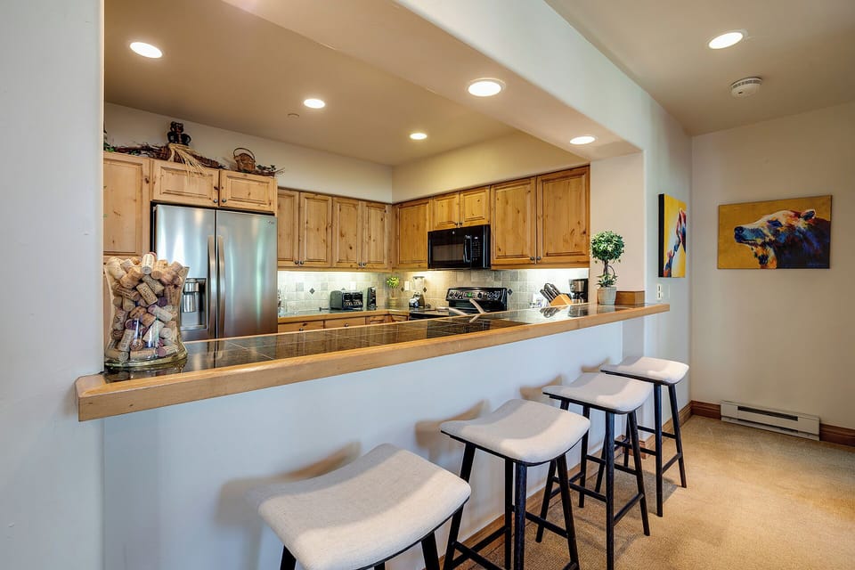Your open kitchen welcomes you with warm wood cabinets, granite counters, and a breakfast bar perfect for morning coffee or evening conversations.