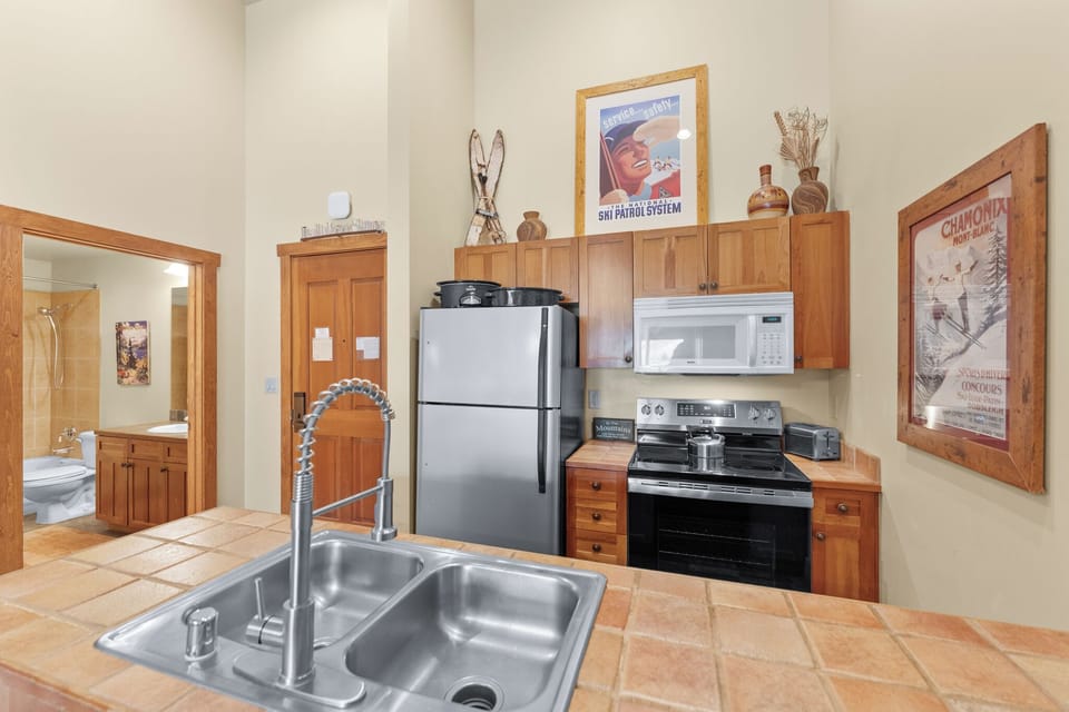 Your fully equipped kitchen features stainless steel appliances and warm wood cabinetry, perfect for preparing meals during your mountain getaway.