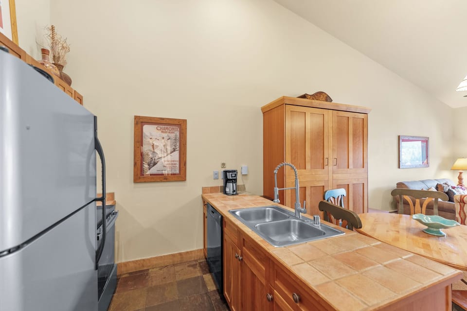 Your fully equipped kitchen features warm wood cabinets, tile countertops, and modern appliances including a dishwasher for effortless meal preparation.