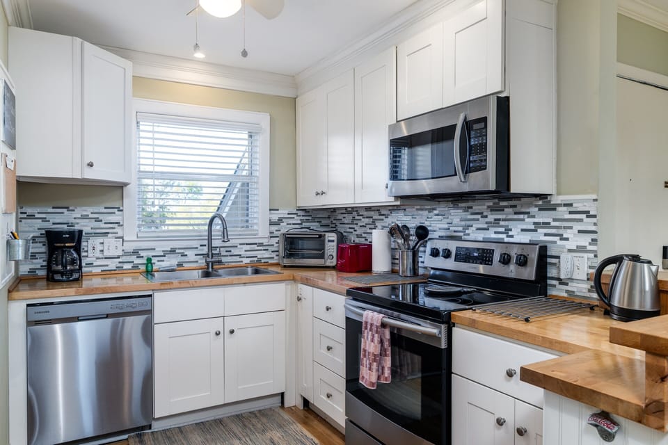 The  kitchen features a tile backsplash,and butcher block counters.