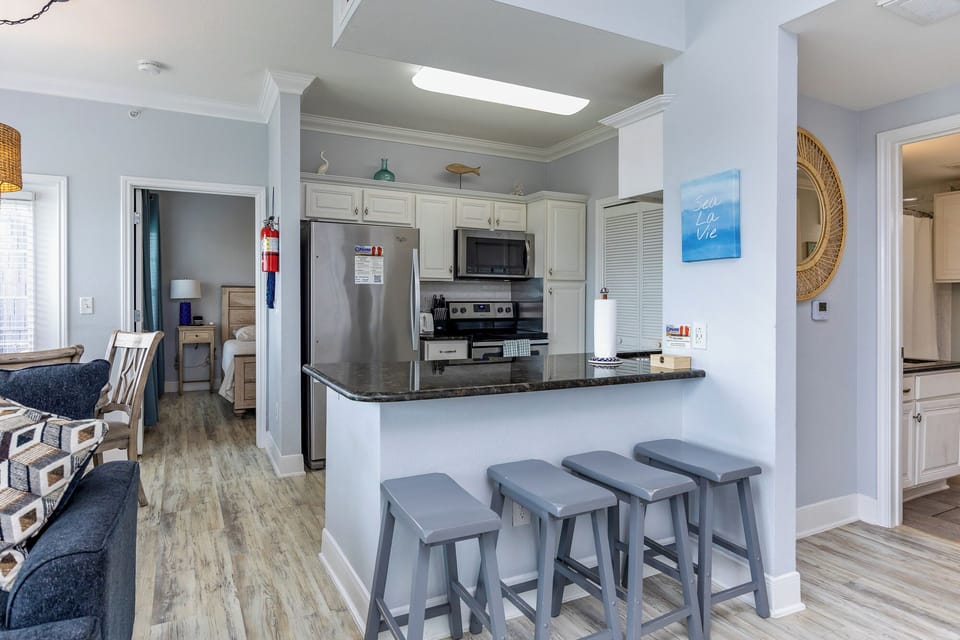 Gather around your stylish kitchen island with modern stools, perfect for morning coffee or casual dining in this bright, open-concept space.