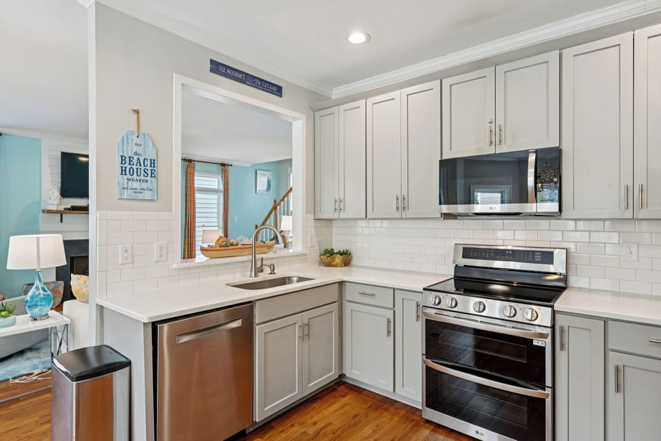 Your coastal kitchen awaits with modern appliances, bright white cabinetry, and charming beach-themed touches that make cooking feel like a seaside retreat.