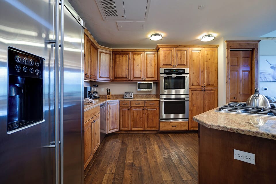 Your spacious kitchen features warm wood cabinets, stainless steel appliances, and granite countertops perfect for preparing memorable meals during your stay.