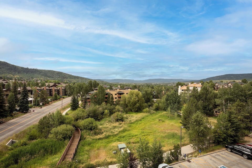 Elevated mountain town vista showcasing the peaceful residential neighborhood with forested hillsides and open meadows in the valley below.