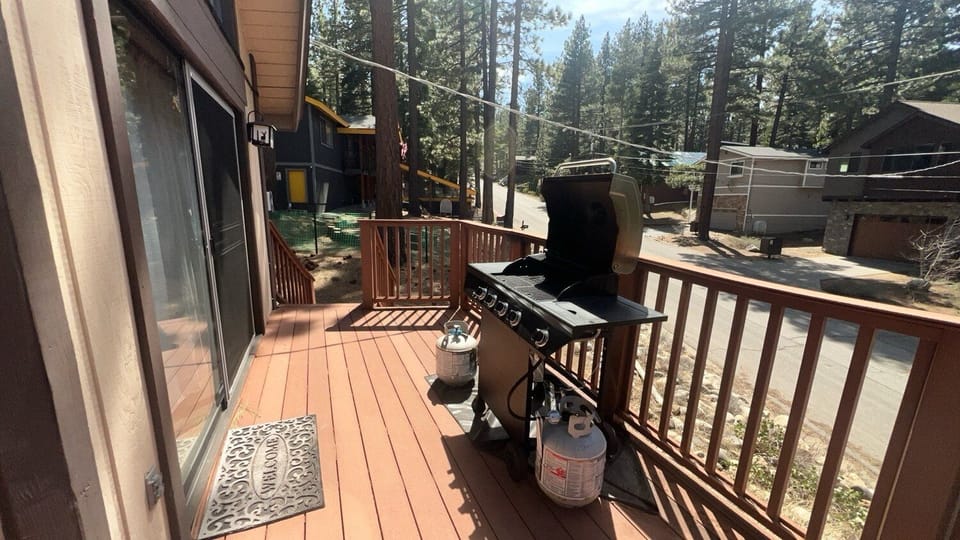 Another look at the deck, with trees, sliding door, deck railing, and stairs.