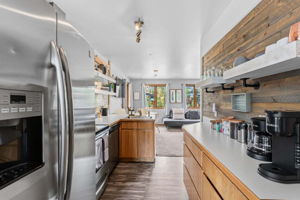 Sleek Social Kitchen — Stainless appliances, a fully stocked setup, and a bar top made for chatting while dinner simmers—easy, warm, and inviting. 🍽️🥂