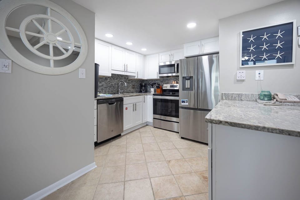 This modern kitchen features sleek stainless appliances, stylish cabinetry, and a charming coastal decor accent