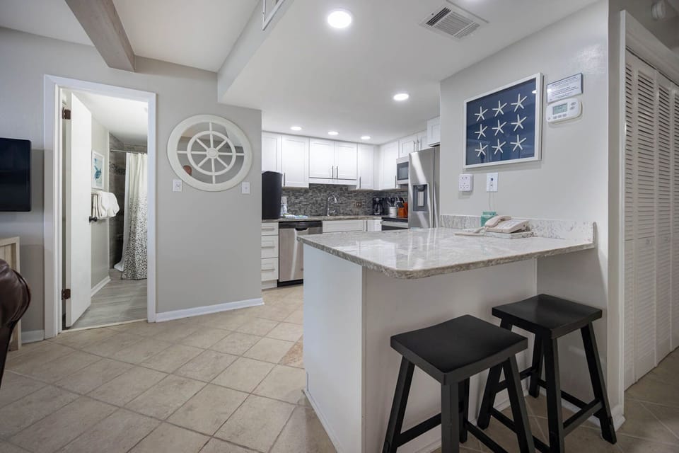 The stylish kitchen features sleek cabinetry, stainless appliances, and a cozy breakfast bar perfect for morning coffee