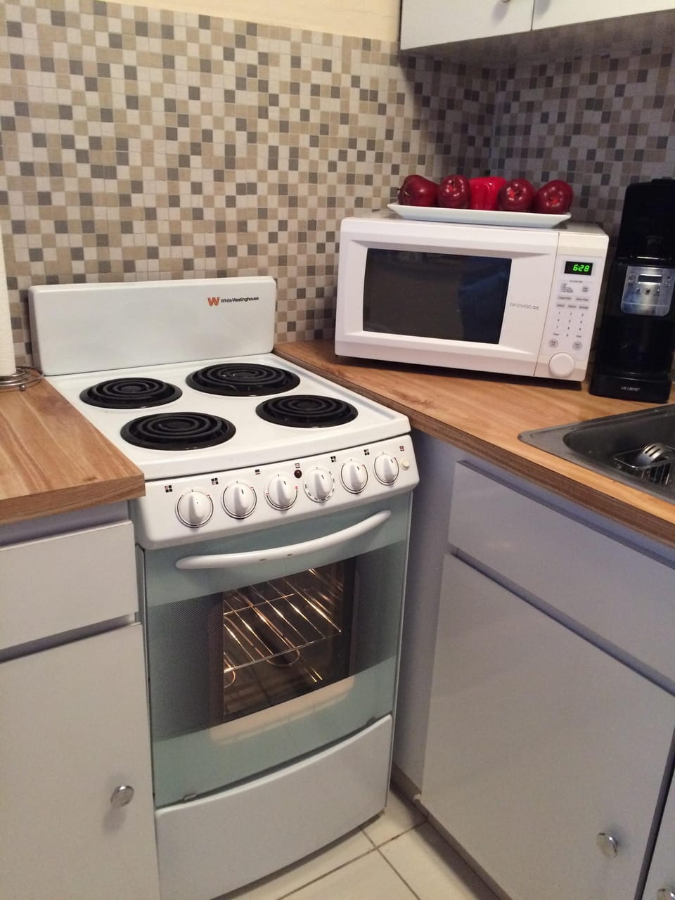 Kitchen stove and microwave. Four cups coffee maker on the right side.