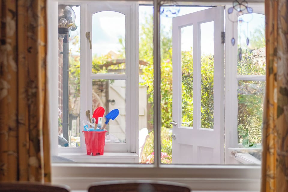 Dining room overlooks sunny courtyard garden with seating and BBQ