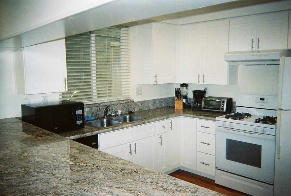 All new kitchen with granite counter, white shaker cabinets, sink, and fixtures 