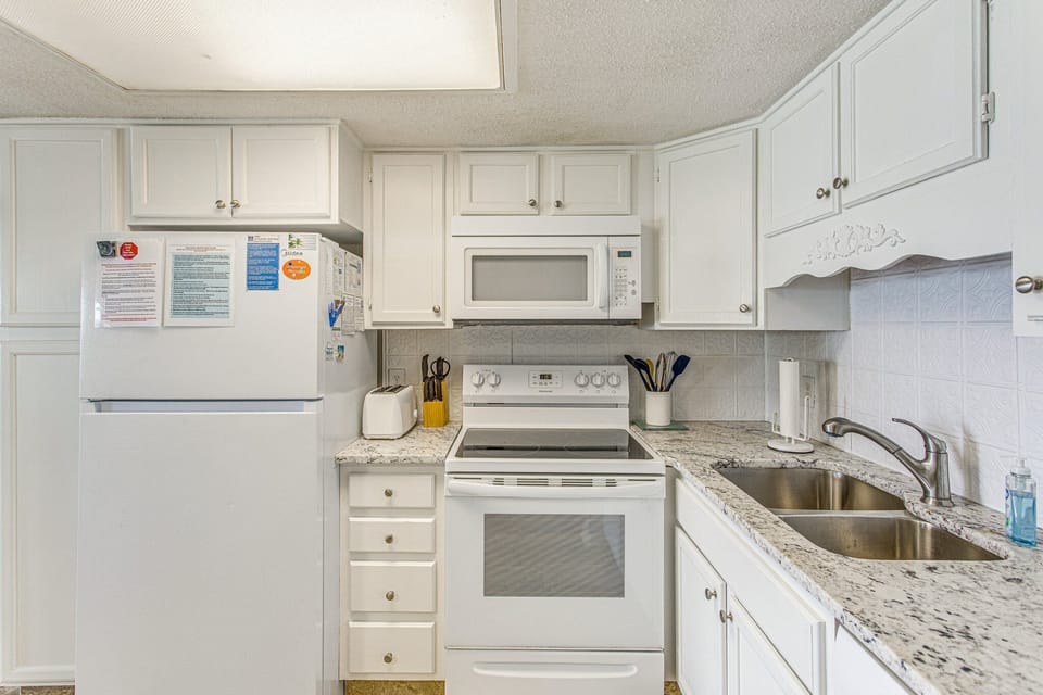Freshly painted cabinets in the kitchen with a granite countertop.