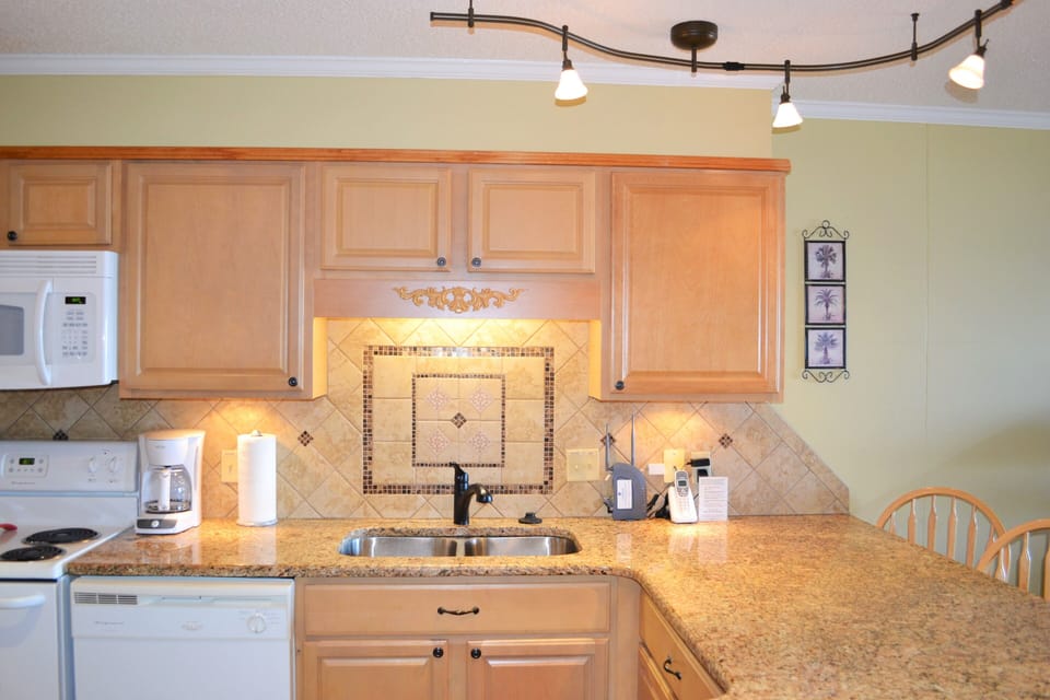 Kitchen with granite countertop and tile blacksplash.