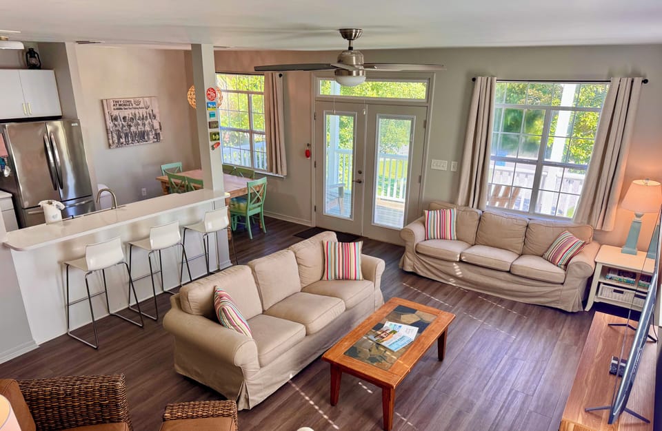 Great room with 65" Smart TV, open floor plan, seated dining, kitchen bar