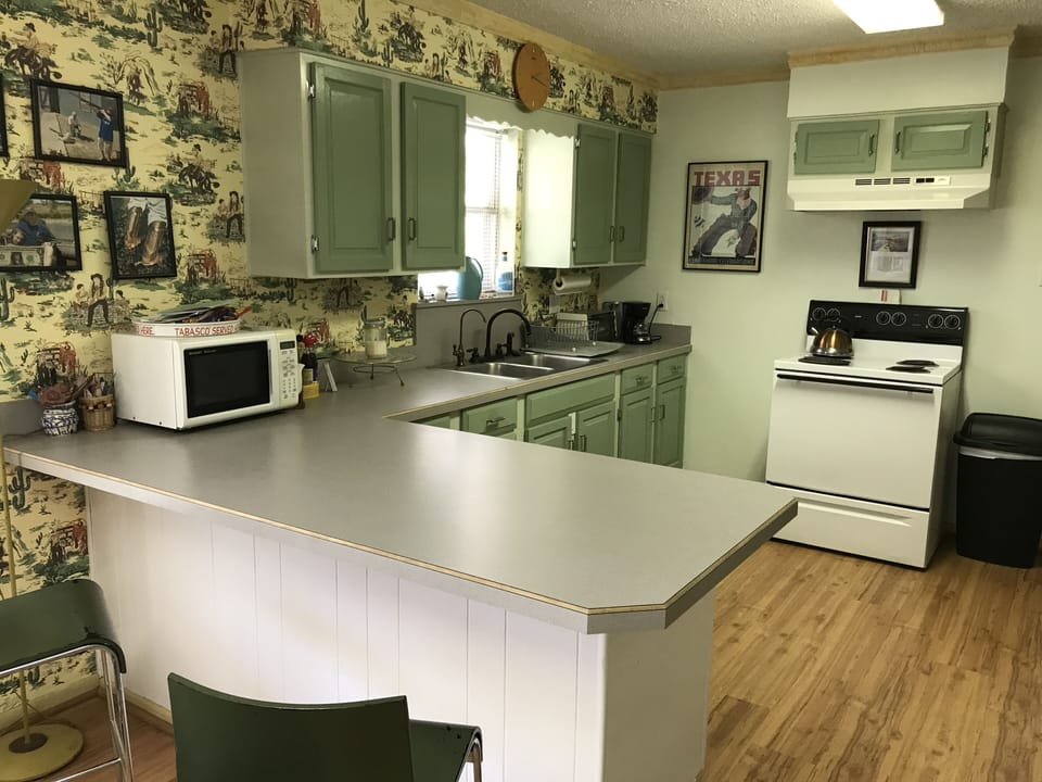 Kitchen, bar dining area with electric stove/oven, microwave and coffee maker.