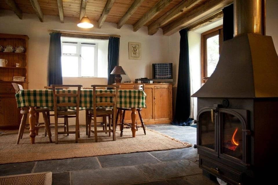 Dining table with double doors leading to terrace at rear and wood burning stove
