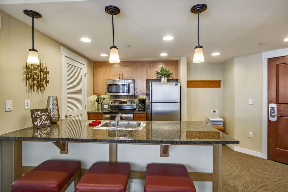 Kitchen with Breakfast Bar, Stools, Refrigerator, and Microwave.