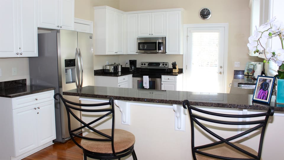 The kitchen features granite counters, custom cabinetry, and seating for 2.