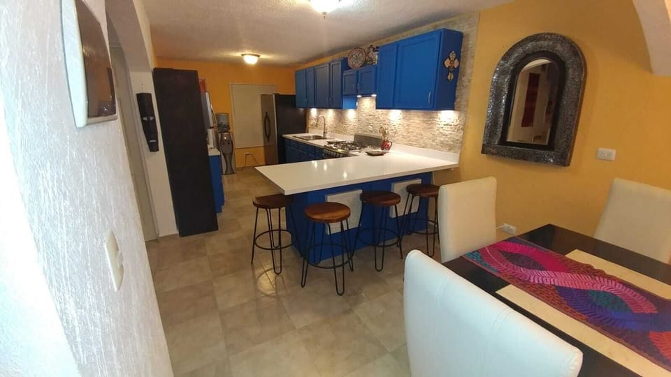 Vibrant blue kitchen with Talavera accents, island bar, quartz & 2 refrigerators