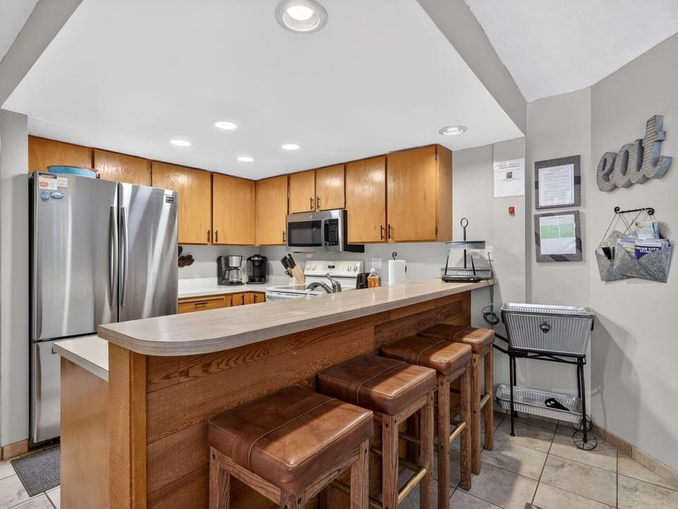 Your fully equipped kitchen features warm wood cabinetry, stainless steel appliances, and breakfast bar seating perfect for morning coffee or casual meals.