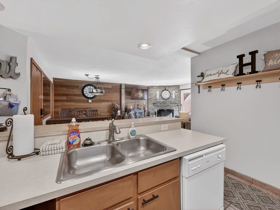 Your fully equipped kitchen flows into a cozy living area with stone fireplace, perfect for preparing meals while connecting with family.