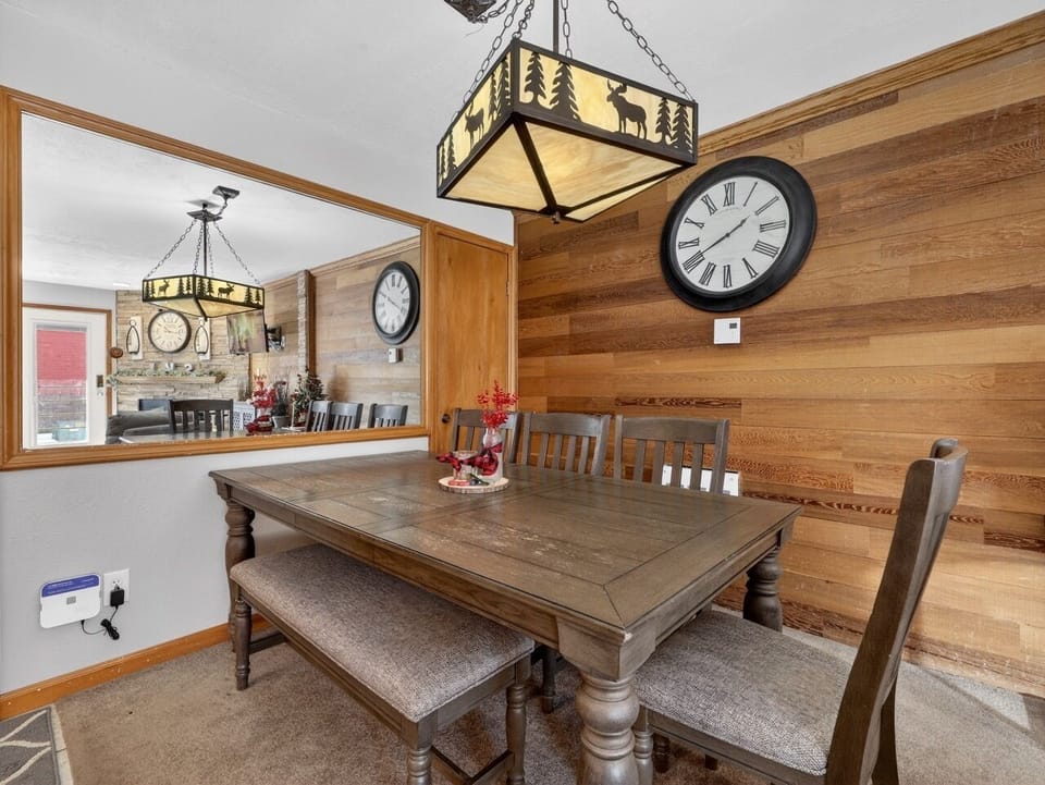 Gather around this rustic dining table where warm wood walls and charming wildlife lighting create the perfect mountain retreat atmosphere for your meals.