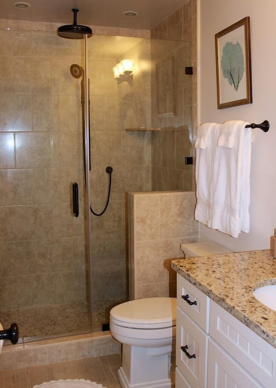 This luxurious bath has a tiled shower w/ a river rock floor & rain shower head.