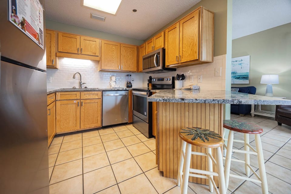 Bright wood cabinetry complements the granite countertops in this fully-equipped kitchen with a convenient breakfast bar